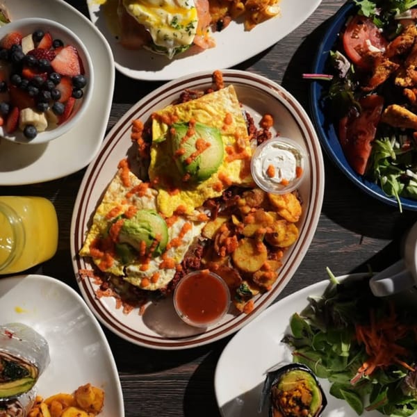 Overhead view of a breakfast spread with omelets, potatoes, fruit, and other dishes.